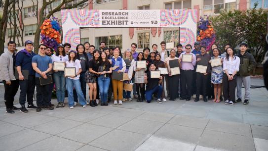 large group photo of research excellence winners in front of exhibit gate