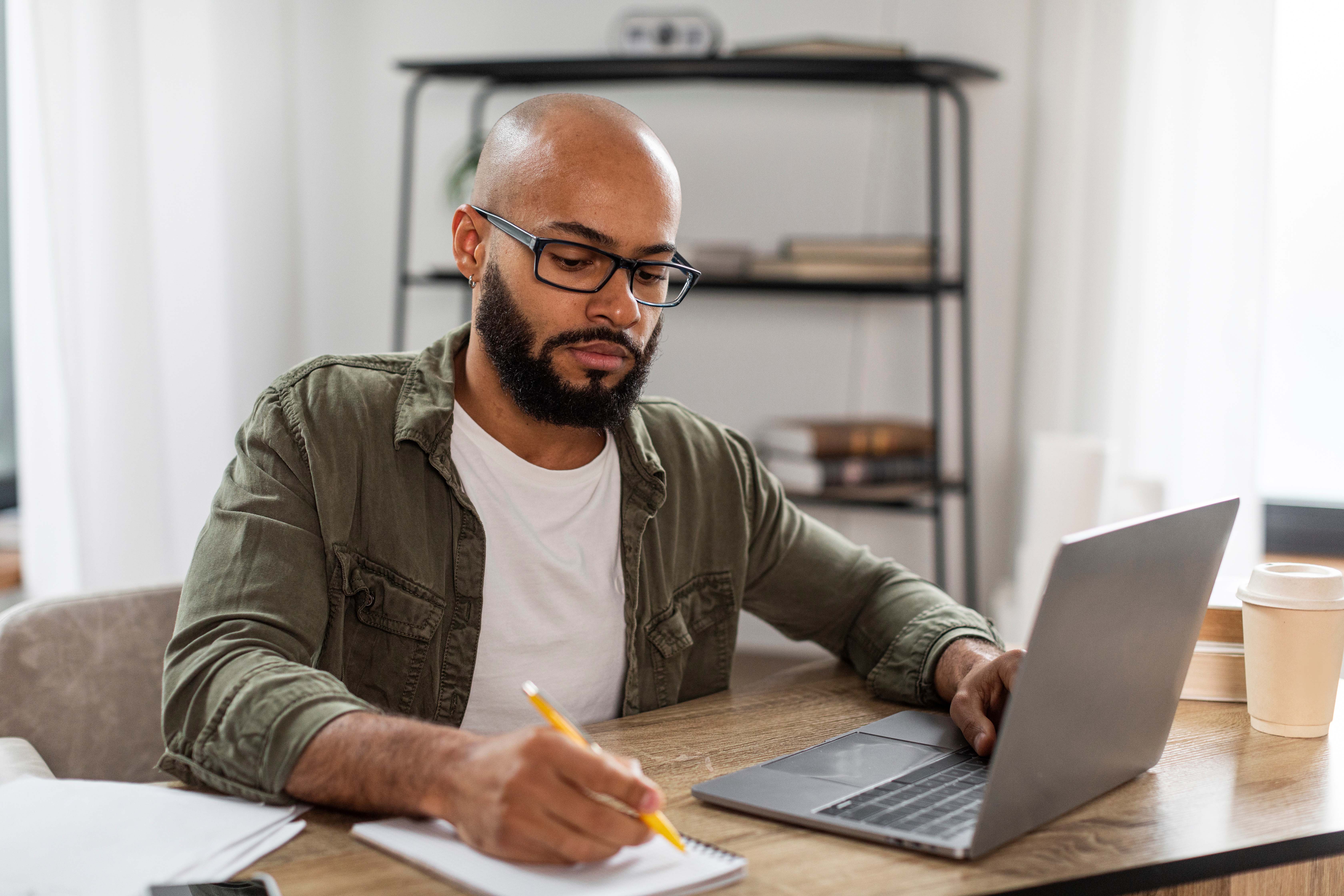 student on laptop writing down notes