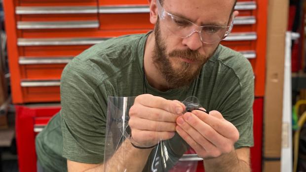 man assembling a plastic face shield