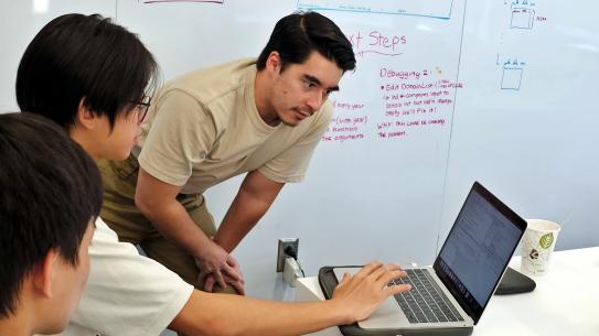 PH.D. student leaning over to look at high school student's laptop