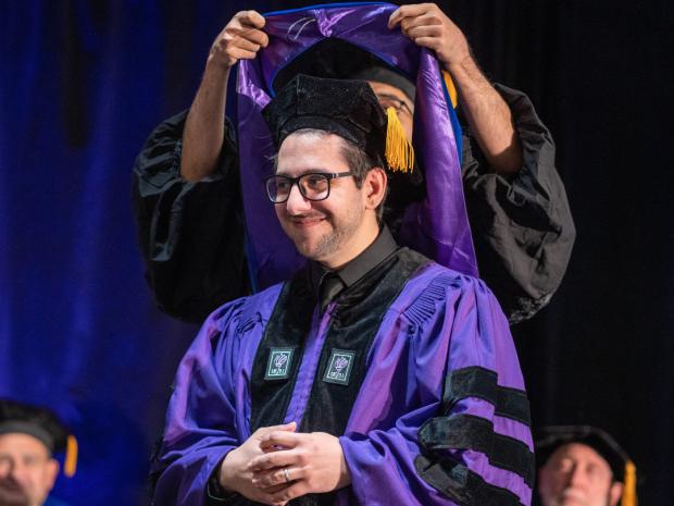 Ph.D. student receiving hood at ceremony