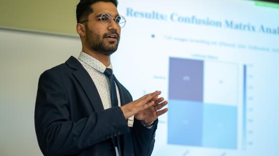 A student gives a presentation in front of a screen.