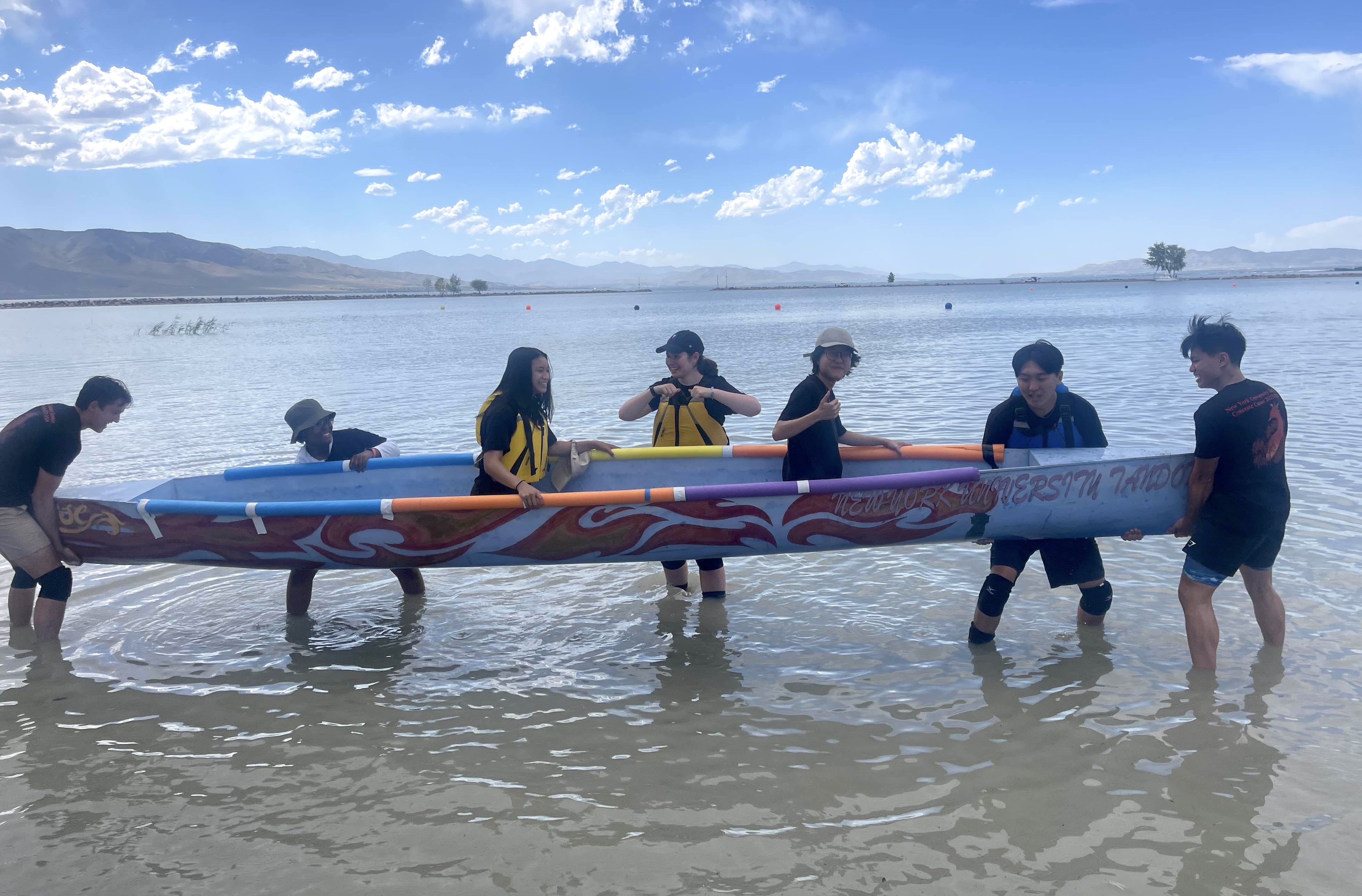 students carrying canoe into water